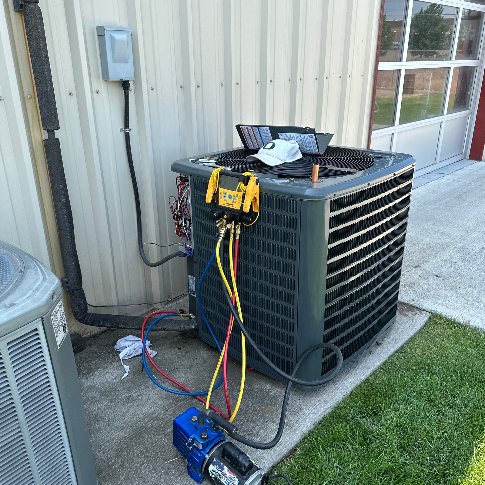 A modern gray residential air conditioner unit installed on a concrete slab next to a home in Tulsa, OK.