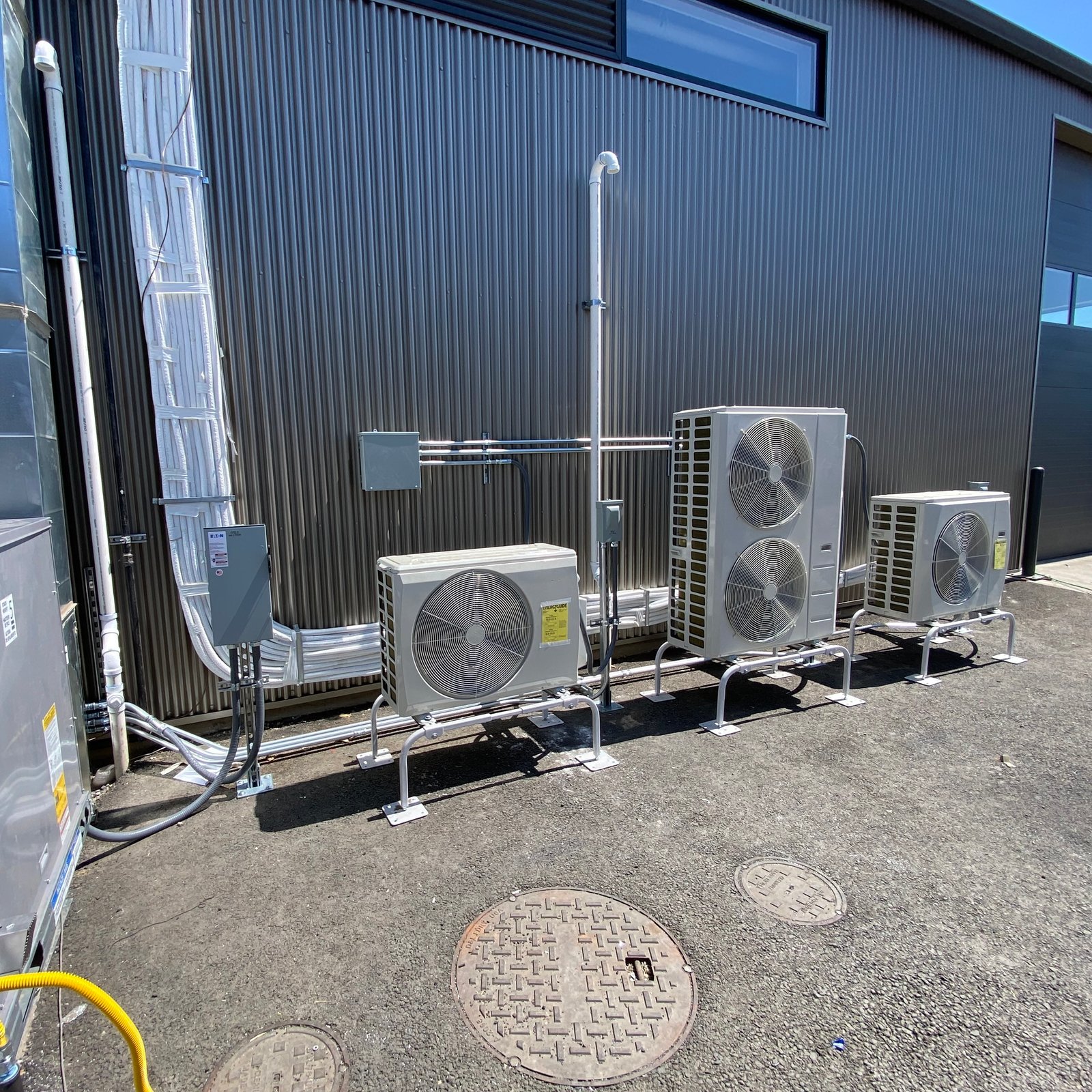 An Air Dynamics of Tulsa technician services an outdoor compressor unit beside a house in Tulsa.